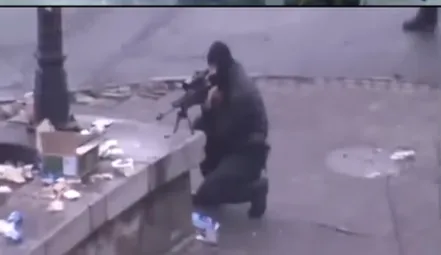 A sniper in black and a balaclava kneeling by the parapet